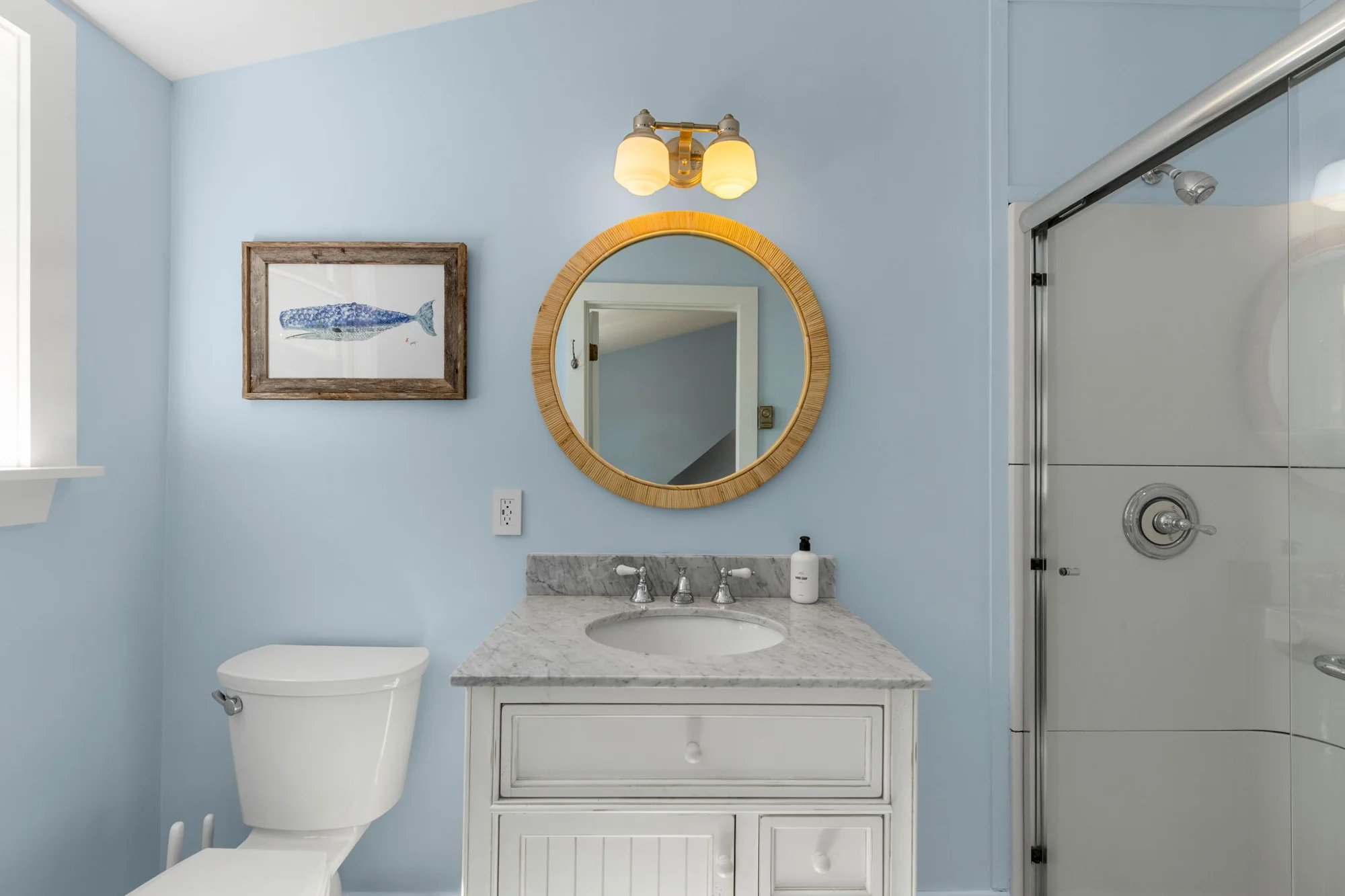 Blue bathroom with round mirror and glass shower