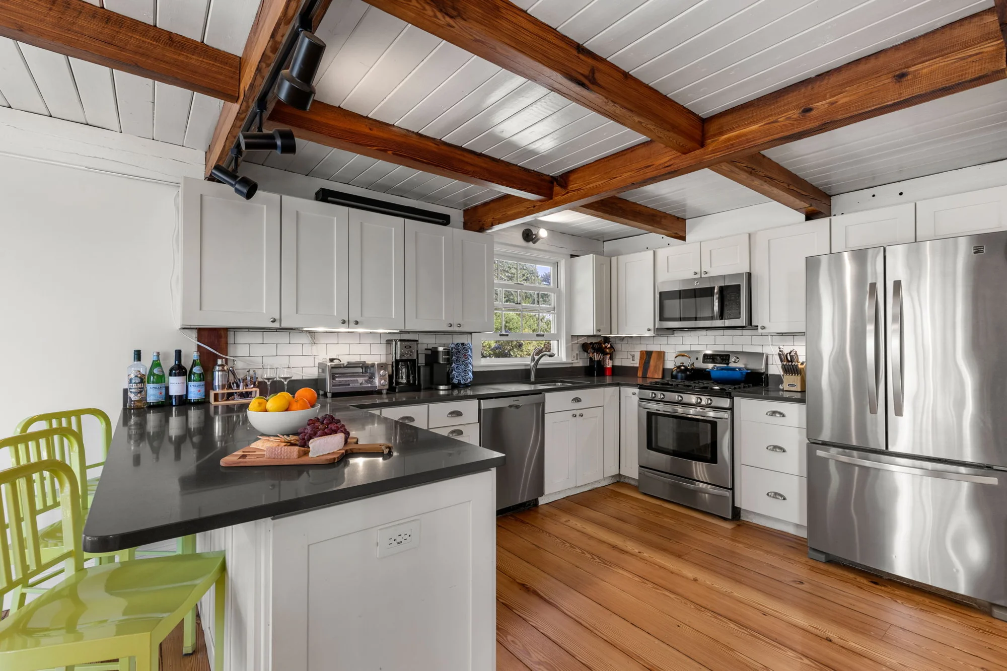 White kitchen with island seating and exposed wood beams